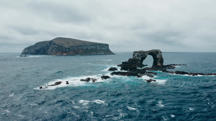 The ocean with water and land with the sky and clouds in the background