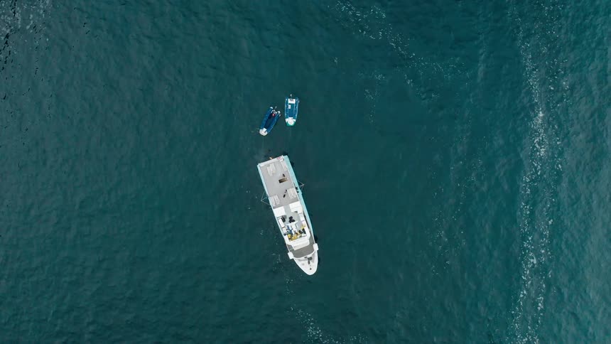 Aerial view of a boat and jet skis floating in the calm ocean waters