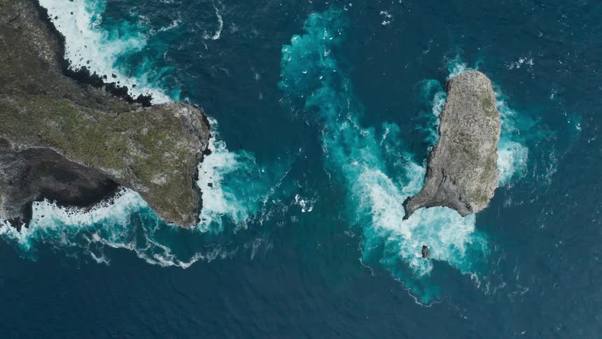 Ocean waves crash against jagged rock formations located along the coast