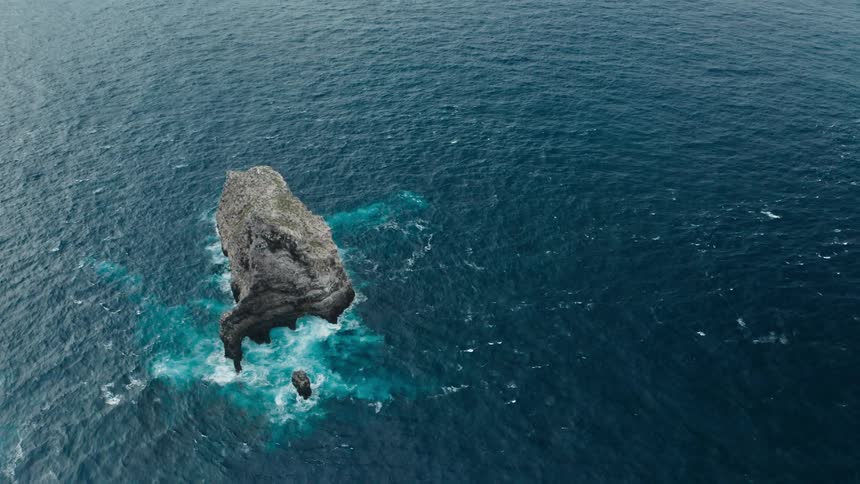 Waves rolling around a cliff in the ocean