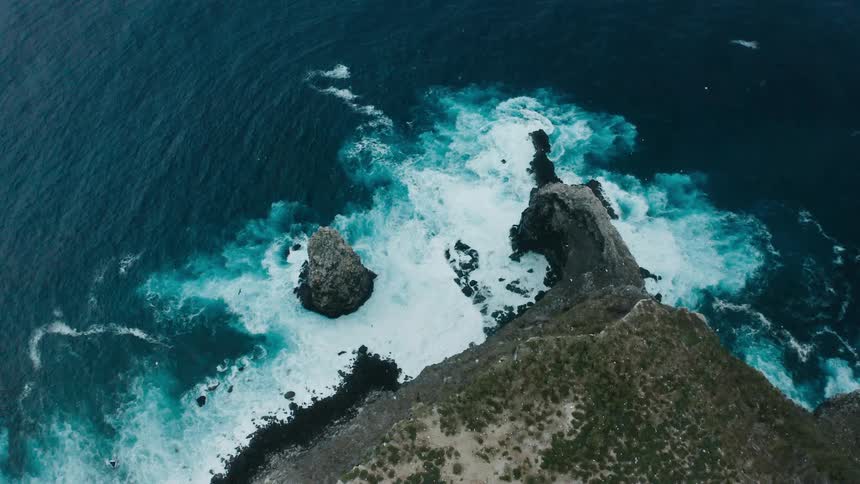 Aerial view of ocean waves crashing on the coastline of a promontory