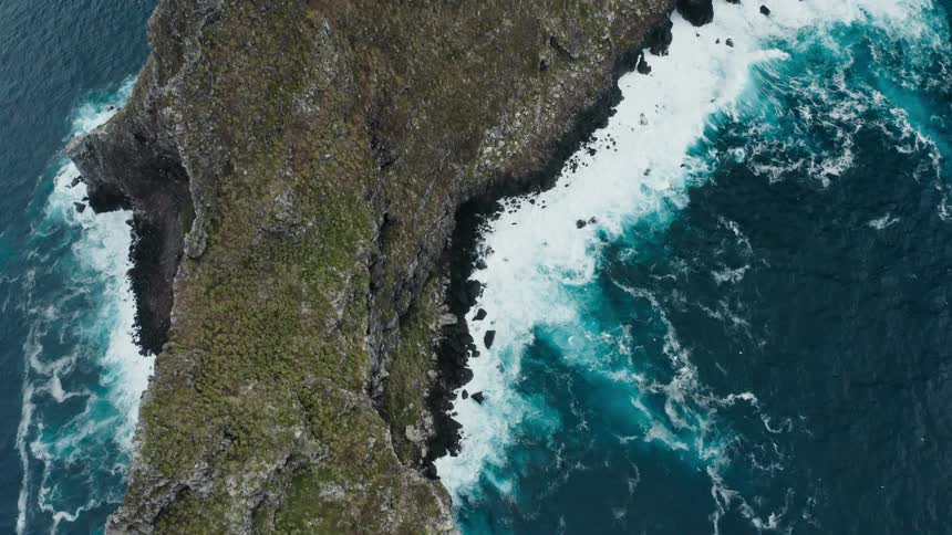 Aerial view of ocean waves crashing on the coastline of a promontory