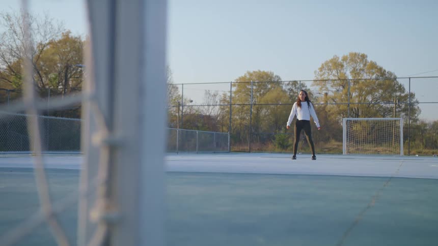 A woman kicks the soccer ball into the net on the court