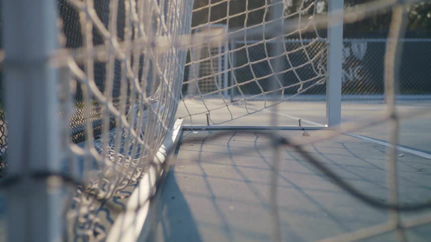 A soccer ball hits the back of a net on a court