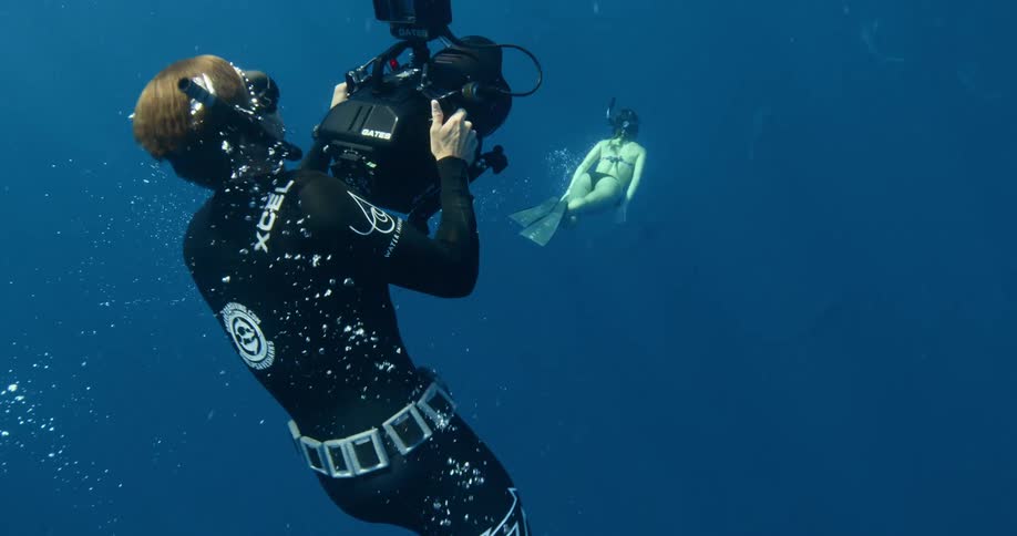Three female divers swim through the open ocean using large flippers