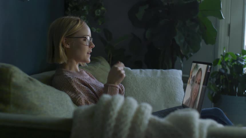 A woman gestures with her hands as she talks to another on a laptop screen