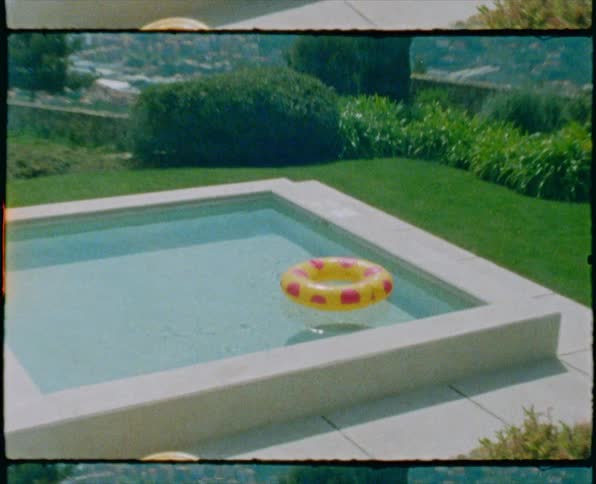 Pool float floats on water in pool set in lawn overlooking misty hills and valleys dotted with town buildings