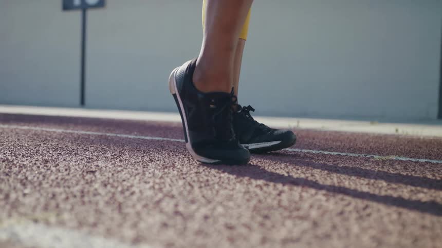 A person loosens up by stretching their leg muscles on a race track