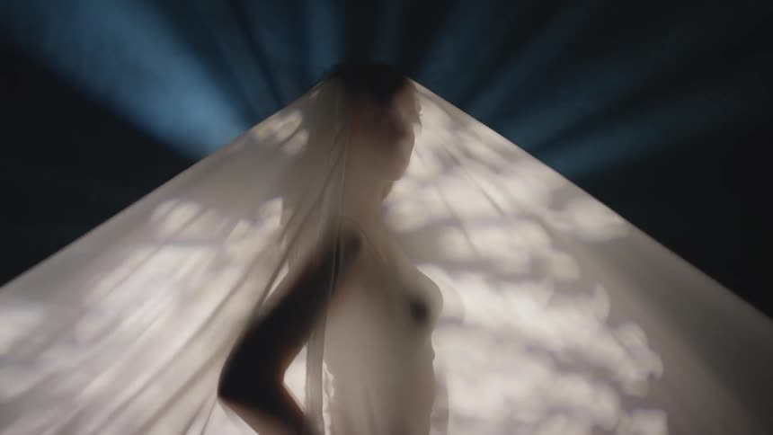 A woman poses under a white cloth lit from below