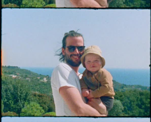 Footage of a dad holding his son outdoors is dispalyed