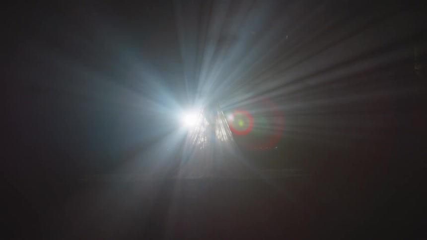 The silhouette of a female standing under a sheet is illuminated by a bright light