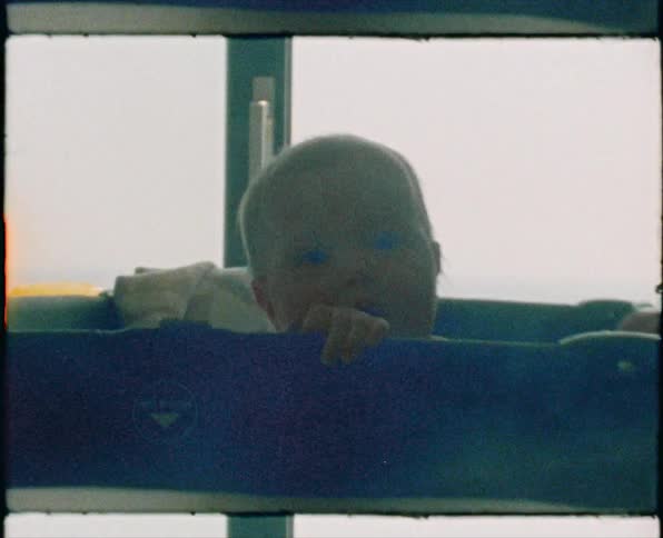Baby peeking over the edge of a corral at home caught on vintage film