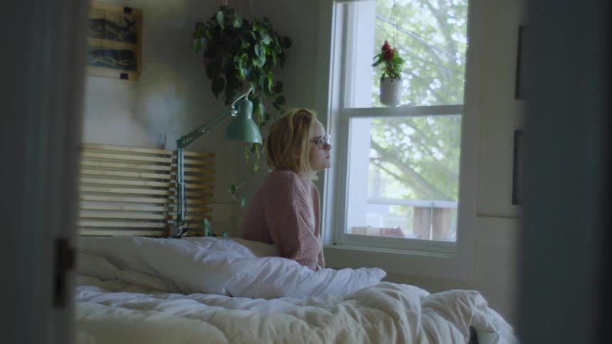 A woman wakes up in her bedroom and puts on her glasses
