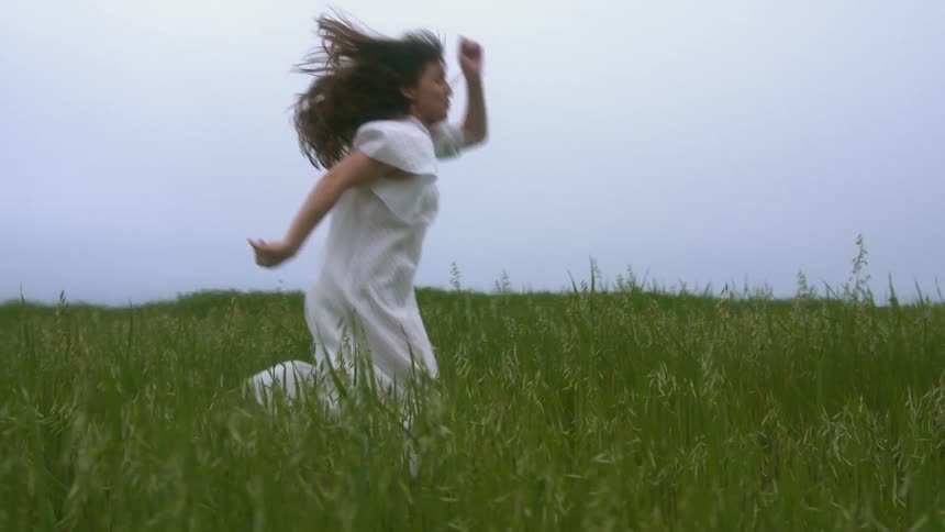 A woman in a dress dances in a large field
