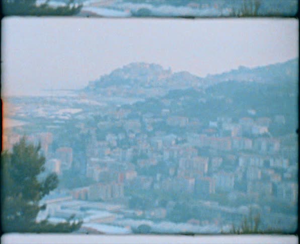 Fog covers large town sitting in valley surrounded by hills and mountains