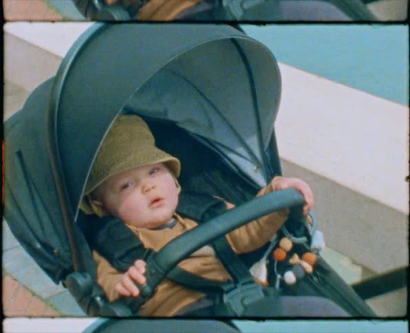 A baby in a baby carriage being wheeled by mom near the marina