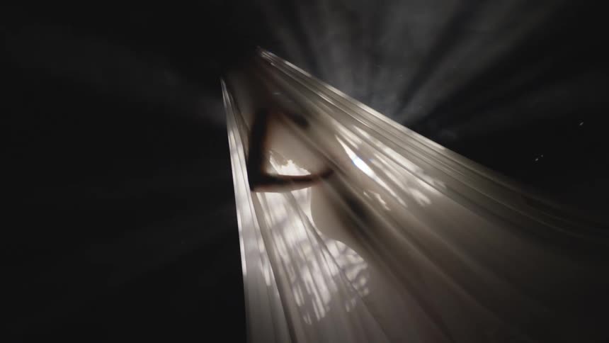 The silhouette of a female figure is visible beneath a translucent sheet