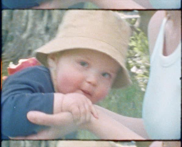 Woman sits on the grass in the forest sharing an apple with a baby