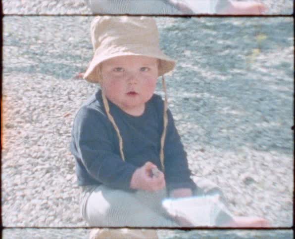 A baby lifts a rock from the ground
