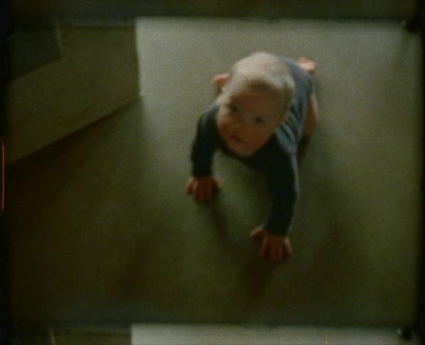 Little blonde baby crawls on the ground in the kitchen