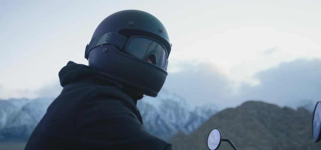A person is sitting on a motorcycle near the mountain range