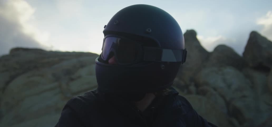 A man is on a motorcycle near mountains