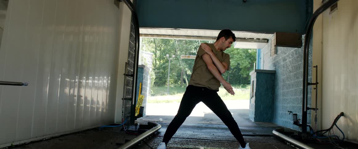 A man dances inside an empty car wash tunnel