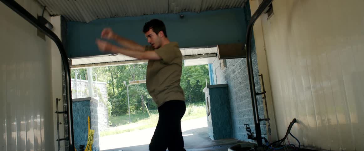 A teenage boy dancing in a garage