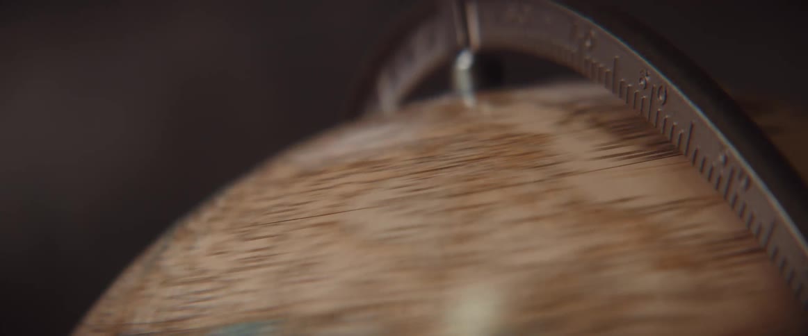 A brown globe held by a metal ring is spinning very fast