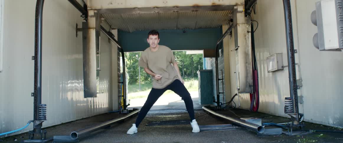 A male dancer dances his way through an empty car wash bay