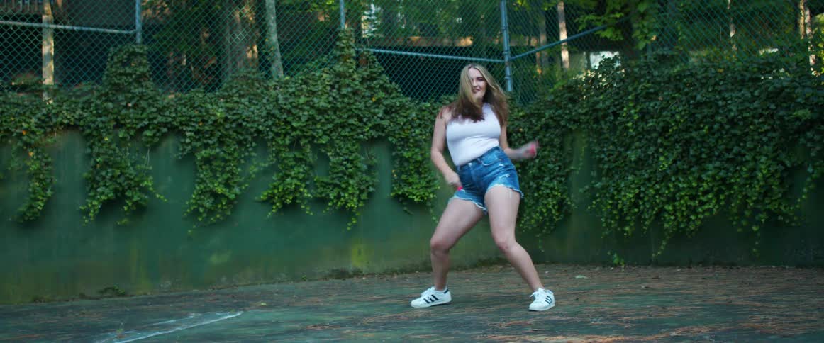 A teenage girl dances in a park