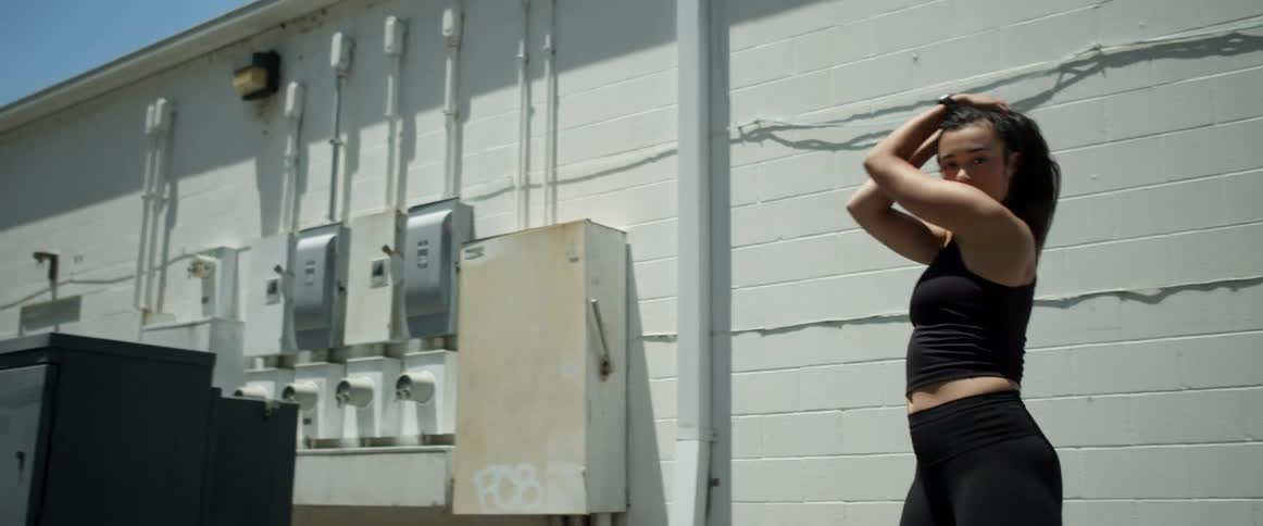 Dancer dances behind building near utility connections