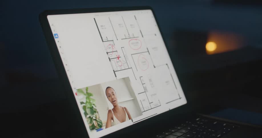A person in a room using a stylus on a laptop with a wall in the background