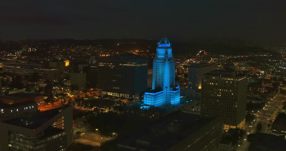 Aerial view of a skyscraper bathed in blue light on the city skyline at night