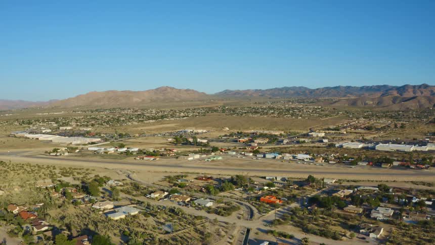 A landscape with houses roads and trees with a mountain range sky and clouds in the background
