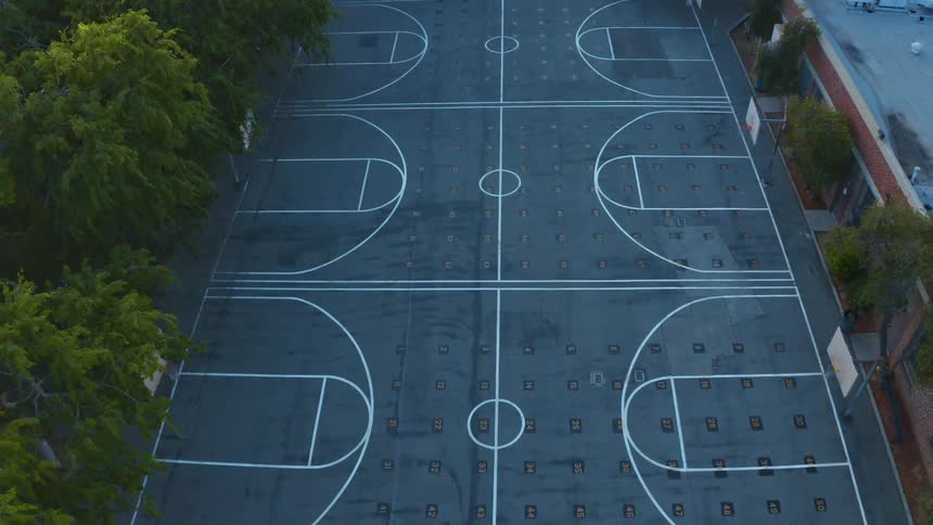 Several basketball courts are in a courtyard surrounded by trees and a large building