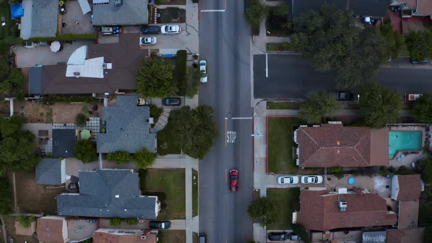 An aerial view of a street in a residential neighborhood shows many houses and little traffic