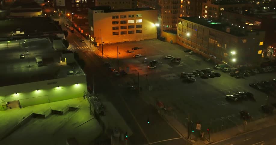 City buildings parking lots and streets glow with lights at night