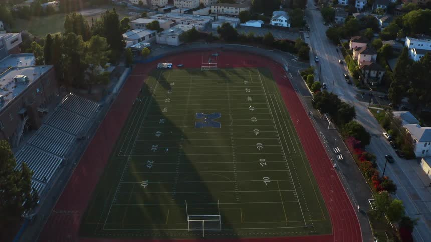 Vehicles pass by a university football stadium situated in a neighborhood