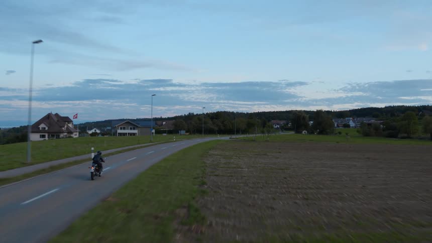 Person rides a bike on country road at dusk