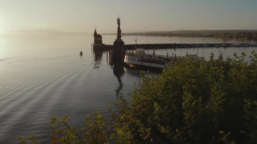 Boat sits in the water near the pier while mountains sit in the distance