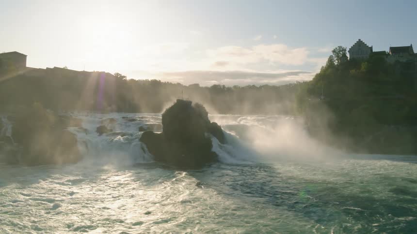 A river flows around a rock formation under a clear daytime sky