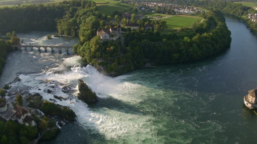 The river water flows over the rocks near the tree lined shore
