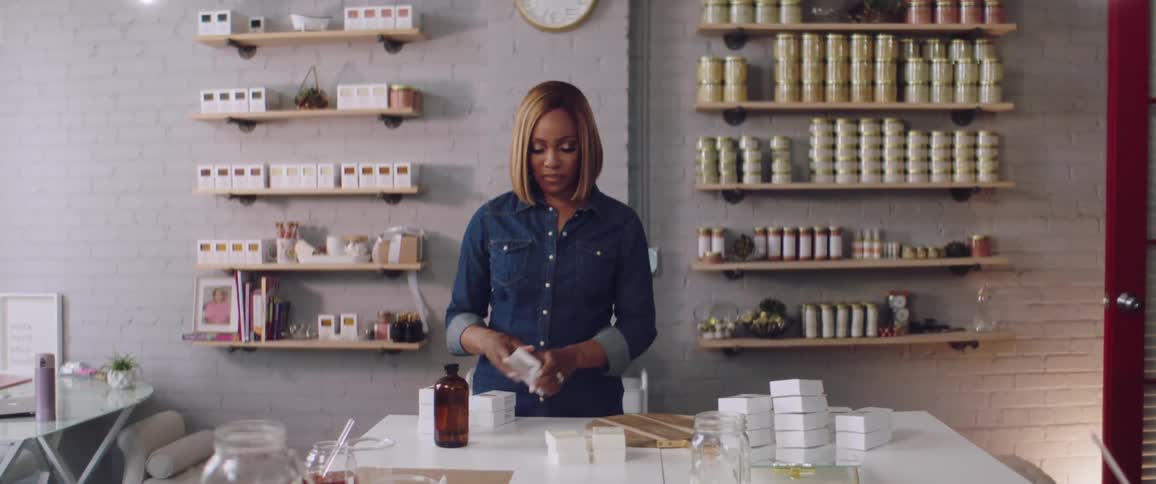 A woman stands in a shop packaging white bars into small boxes