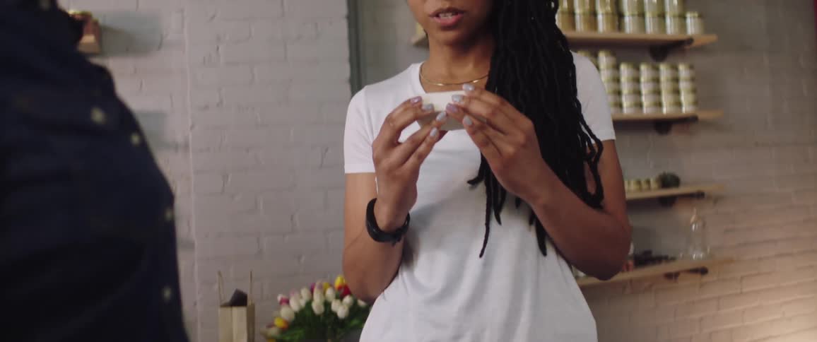 A woman hands a customer a bar of soap to smell in a store