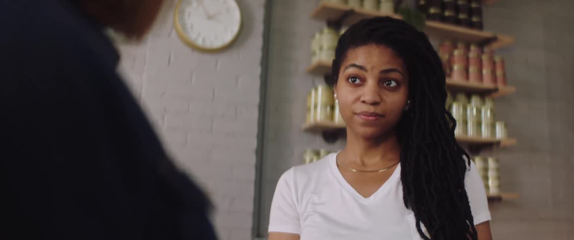 A female customer reacts as a sales woman picks up a jar and talks to her