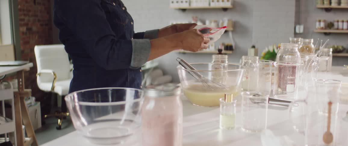 Powder is scooped out of a plastic bag and added to a bowl of liquid