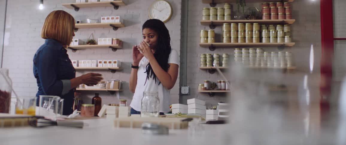 A young woman picks up and smells an item while in a small shop