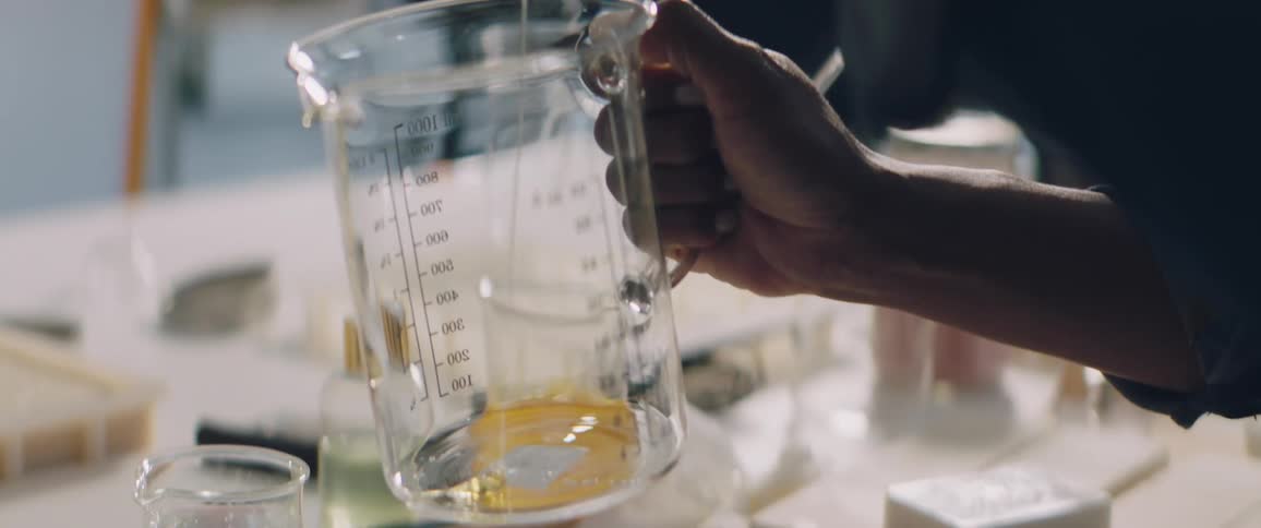 A person pouring honey into a glass measuring cup in a kitchen