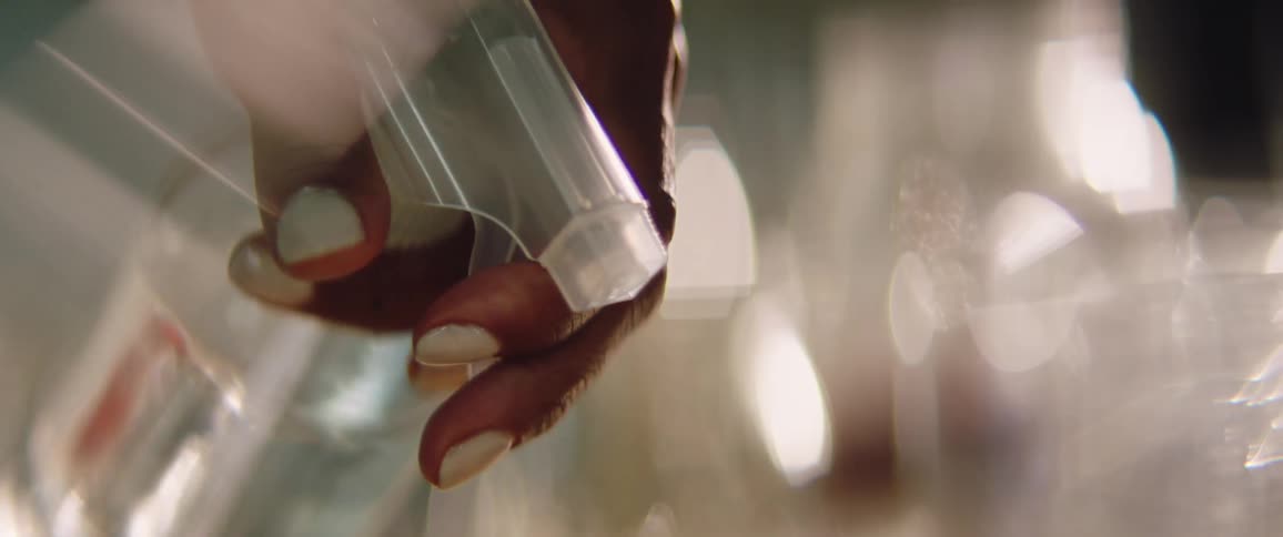 A woman uses a clear spray bottle to spritz glass containers with water